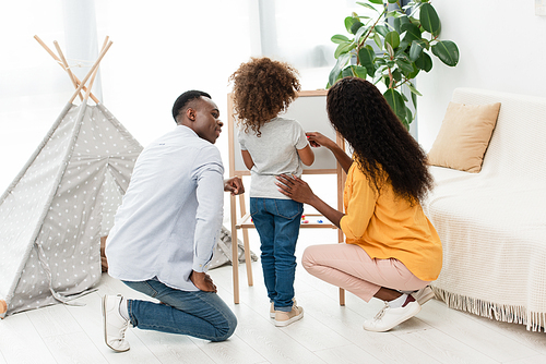 african american man looking and curly daughter near brunette wife