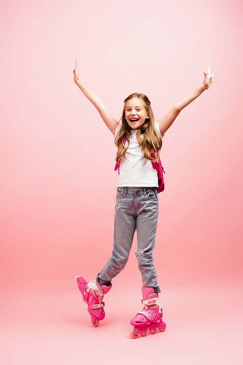 excited girl in white t-shirt, jeans and rolling skates  with raised hands on pink