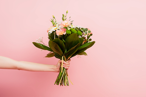 cropped view of female hand with bouquet of flowers isolated on pink