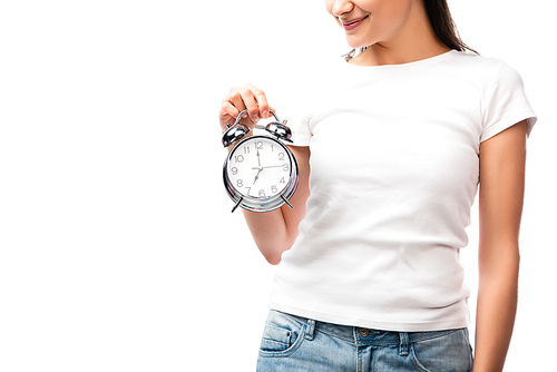 partial view of young woman in white t-shirt holding vintage alarm clock isolated on white