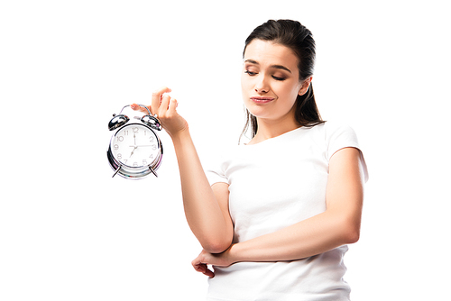 dissatisfied woman in white t-shirt looking at retro alarm clock isolated on white