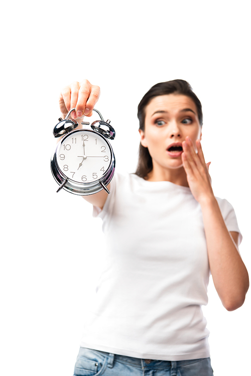 selective focus of shocked woman in white t-shirt looking at retro alarm clock isolated on white