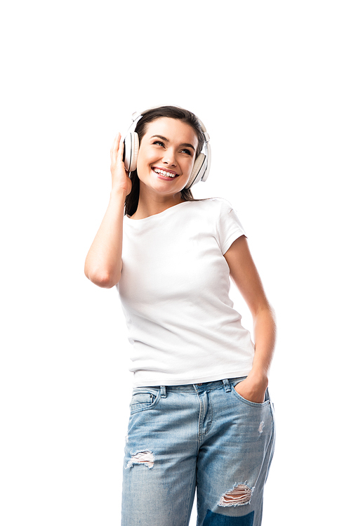 young woman in white t-shirt and wireless headphones standing with hand in pocket isolated on white