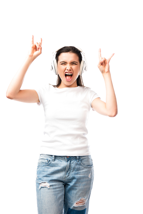 young woman in white t-shirt and wireless headphones showing rock sign isolated on white