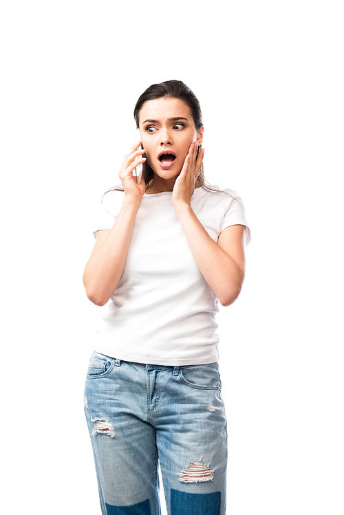 shocked young woman in white t-shirt talking on smartphone isolated on white