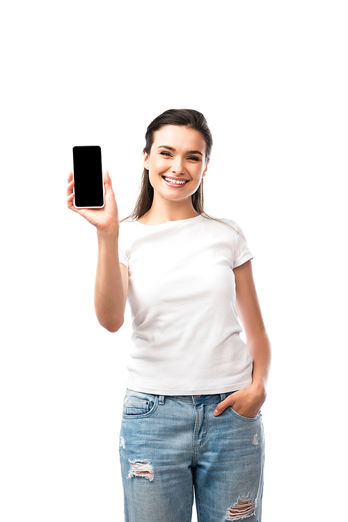 woman in white t-shirt standing with hand in pocket and holding smartphone with blank screen isolated on white