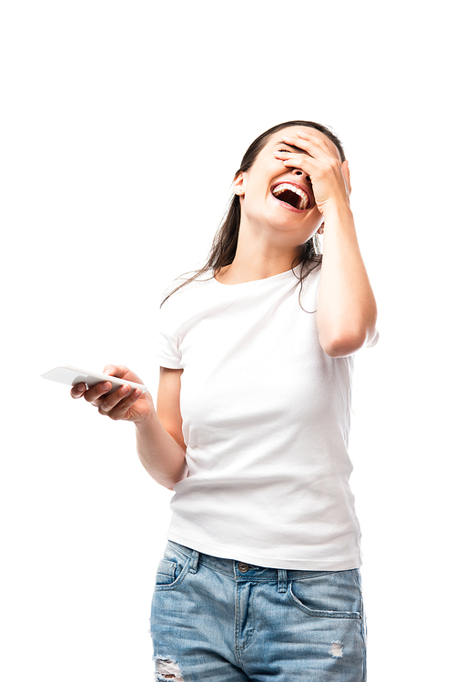 young woman covering face, laughing and holding smartphone isolated on white