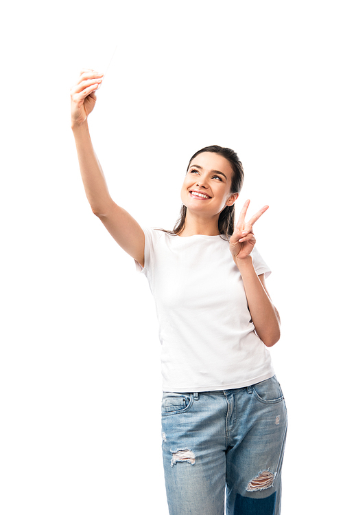 brunette woman in white t-shirt taking selfie and showing peace sign isolated on white