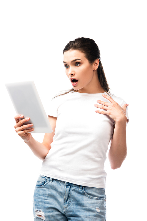 shocked brunette woman in white t-shirt using digital tablet isolated on white