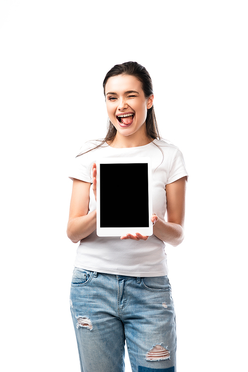 brunette woman in white t-shirt holding digital tablet with blank screen and sticking out tongue isolated on white