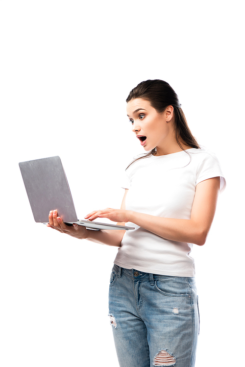 shocked brunette woman in white t-shirt using laptop isolated on white