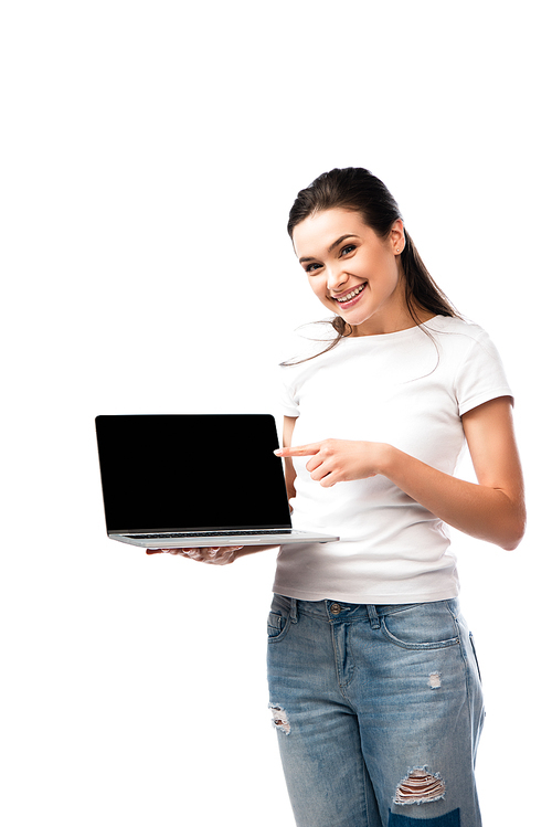 brunette woman in white t-shirt pointing with finger at laptop with blank screen isolated on white