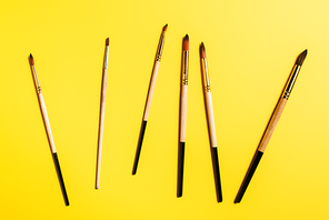 Top view of wooden paintbrushes on yellow surface