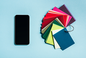 Top view of smartphone and color samples on blue surface