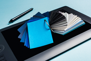 Close up view of color samples on graphics tablet and stylus on blue background