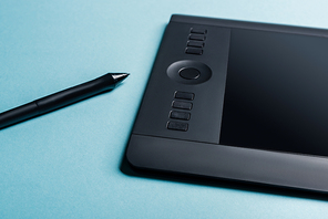 Close up view of graphics tablet  and stylus on blue surface