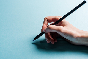 Cropped view of designer holding pencil on blue surface