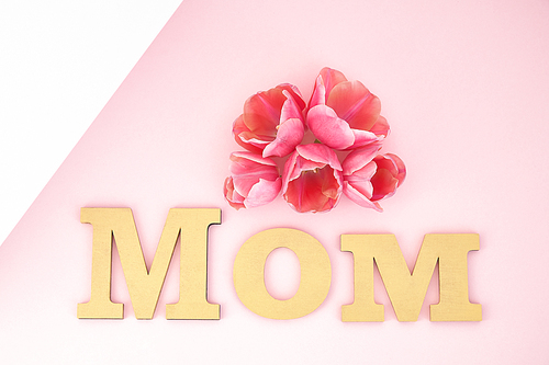 top view of tulips and mom lettering on pink and white background
