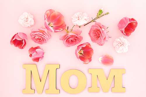 top view of blooming spring flowers and mom lettering on pink background