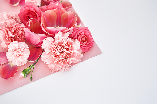 top view of roses, tulips and carnations on pink and white background