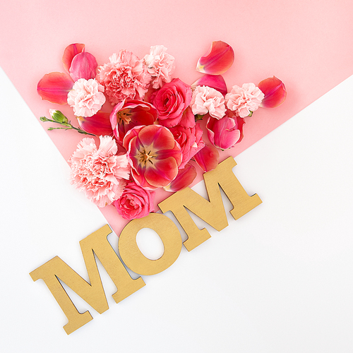 top view of roses, tulips and carnations on pink and white background with mom lettering