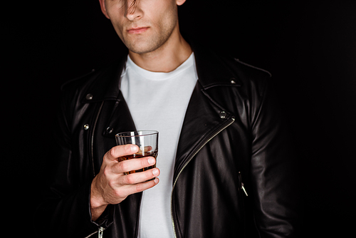 cropped view of trendy man holding glass with whiskey isolated on black