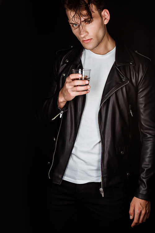 trendy man holding glass with whiskey isolated on black