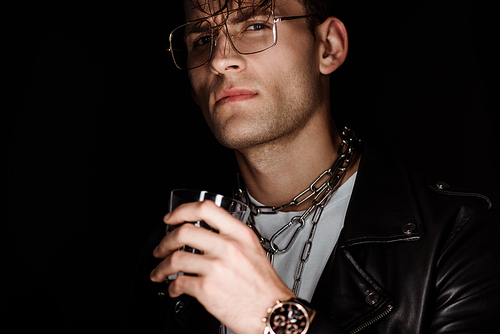 selective focus of stylish man in eye glasses holding whiskey isolated on black