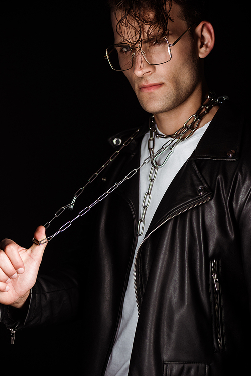 stylish man touching metallic chains on neck isolated on black