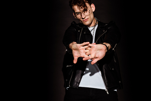 selective focus of young man in glasses with clenched hands on black