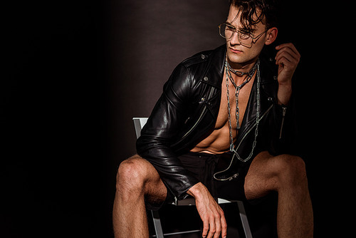 pensive young man in leather jacket sitting on black