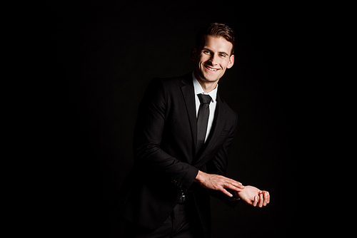 happy businessman in suit smiling isolated on black