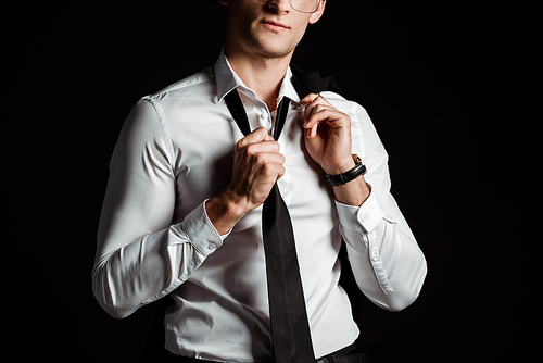 cropped view of businessman taking off tie isolated on black