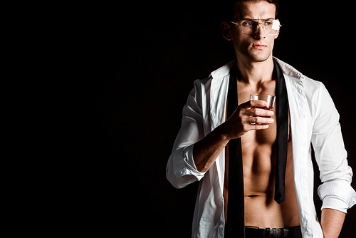 sexy businessman in glasses holding glass with whiskey isolated on black