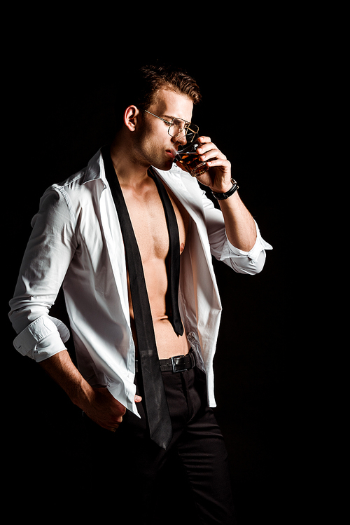 sexy businessman in glasses drinking whiskey isolated on black