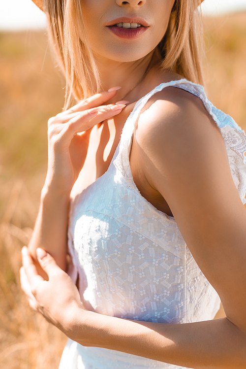 cropped view of sensual young woman in summer outfit touching neck in sunshine