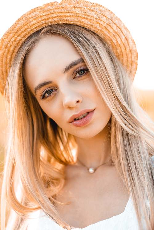 portrait of young blonde woman in straw hat  in sunshine