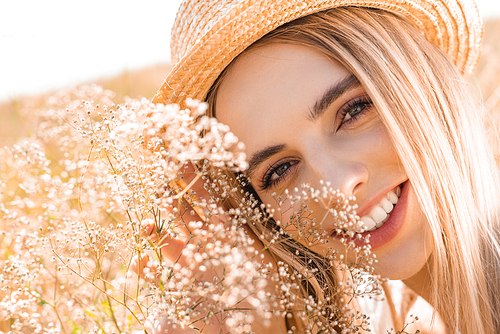 portrait of young blonde woman in straw hat  near wildflowers, selective focus