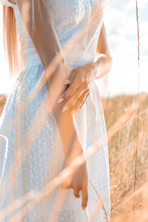 cropped view of woman in white dress standing in grassland, selective focus
