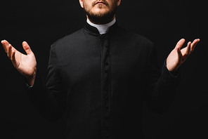 cropped view of priest with outstretched hands isolated on black