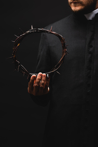 cropped view of priest holding wreath with spikes in hand isolated on black