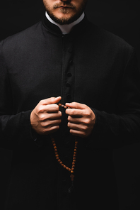 cropped view of priest holding rosary beads isolated on black