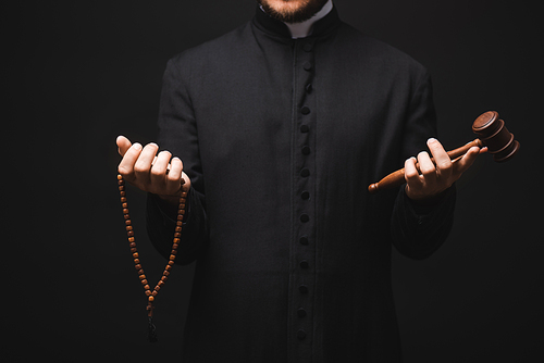 cropped view of priest holding wooden gavel and rosary beads in hands isolated on black