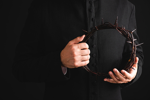 cropped view of priest holding sharp wreath with spikes isolated on black