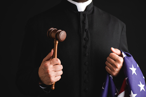 cropped view of priest holding wooden gavel and american flag isolated on black