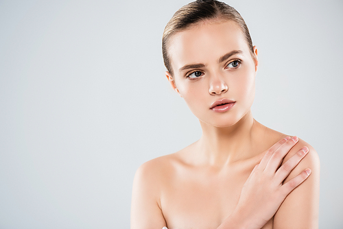 naked young woman looking away and touching shoulder isolated on grey