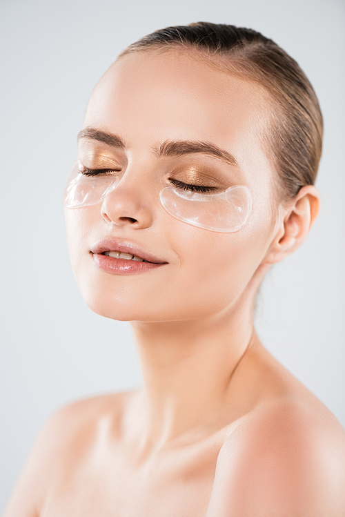 attractive and cheerful woman with closed eyes and eye patches isolated on grey