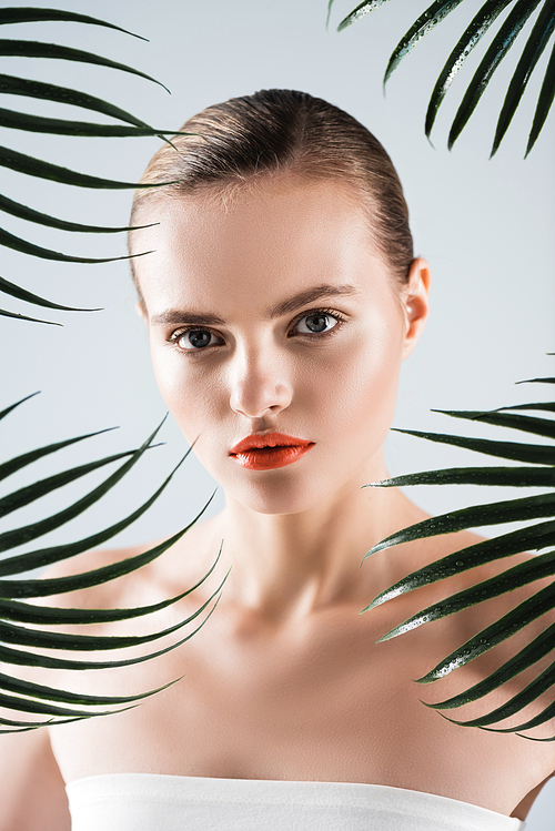 pretty woman with makeup  near palm leaves on white