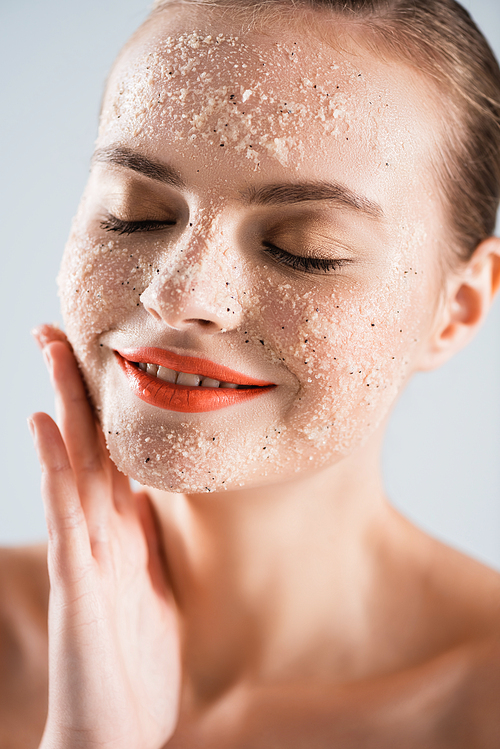 close up of happy young woman applying scrub isolated on white