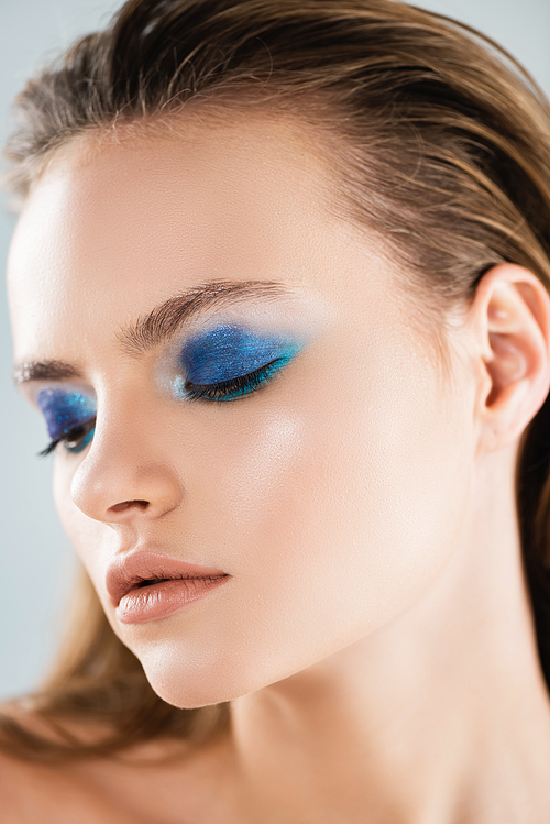 close up of attractive young woman with blue eye shadow isolated on white